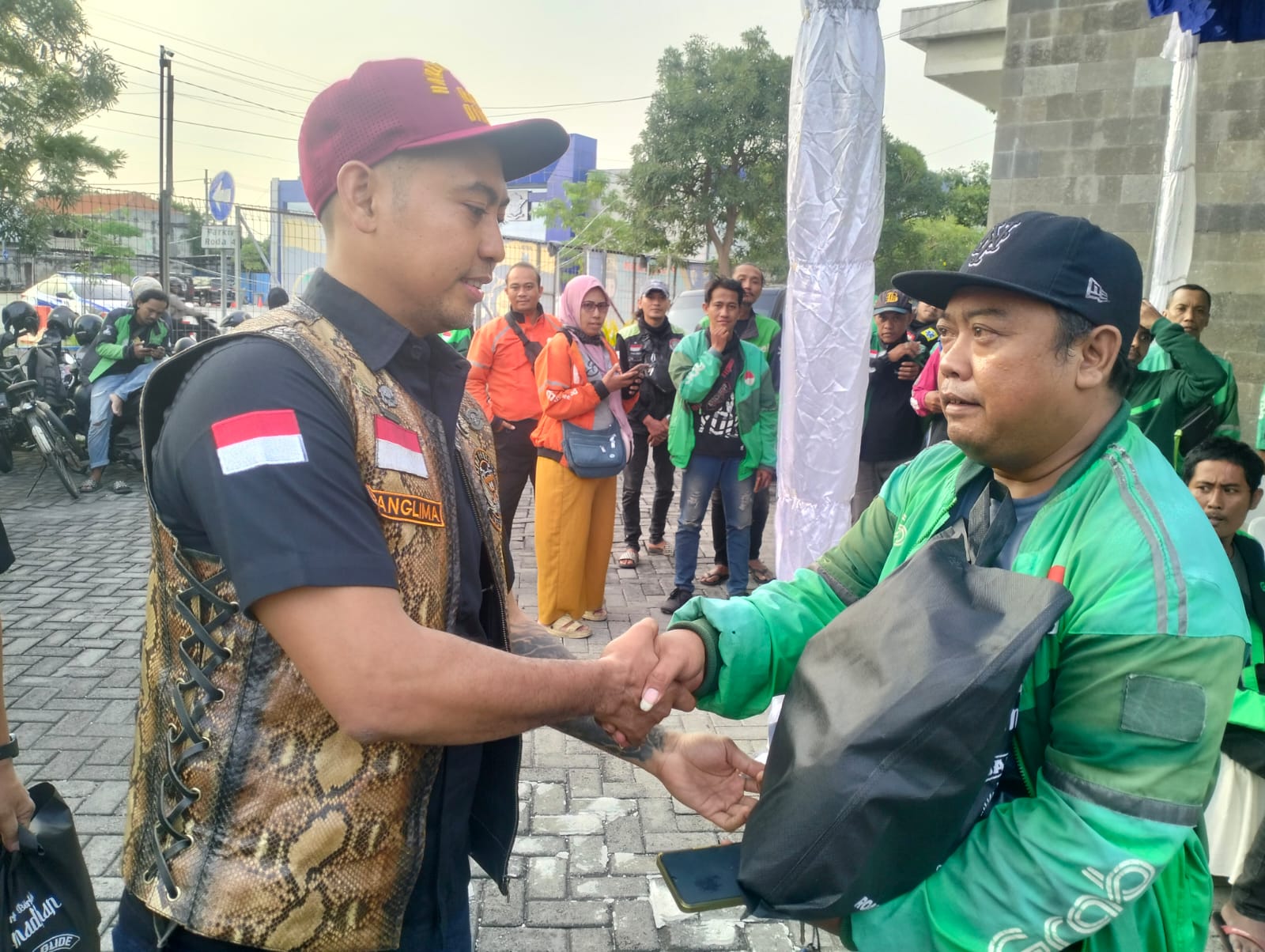 Panglima RGOG, Yoseph George Lawansuka, menyerahkan paket sembako kepada ojek online di Satpas Colombo. Komunitas ini menjelang lebaran Idul Fitri sedang rutin menggelar baksos di beberapa titik di Surabaya. (istimewa/ surabayakabarmetro.id)